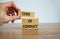 Male hand placing a block with word `code` on top of a blocks with words `code of conduct`. Beautiful wooden table, white