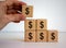 Male hand placing a cube with dollar sign on top of a pyramid. Beautiful white background