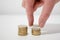 Male hand placing Euro coins in two stacks on a white desk