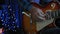 Male hand is playing on guitar strings with guitar pick, close up. Guitarist plays on electric guitar in dark room with blurry lig