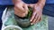 A male hand pounding many kinds of fresh herbs in a stone mortar.