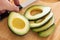 Male Hand Prepares Fresh Cut Avocado on Wooden Cutting Board