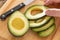 Male Hand Prepares Fresh Cut Avocado on Wooden Cutting Board