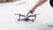 Male hand presses a button on a gray drone standing on the ground