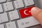 Male hand pressing keyboard button with flag of Turkey on it. Online international business concept