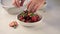 Male hand put strawberries in plate Fresh strawberries in bowl close up