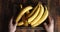 Male hand put a wooden tray with fresh bananas.