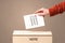 Male hand putting vote into a ballot box, on grungy background