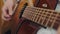 male hand rearranges chords on acoustic guitar close up.