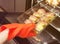 Male hand in a red silicone glove tack puts a glass tray with stuffed champignons in the oven