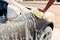 Male hand rubbing the car with foam, carwash