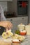 Male hand seen making pasta with dough roller and flour on kitchen counter