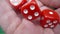 Male hand shakes red dice in slow motion against the background of a green roulette table in a casino. Man gambler