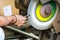 Male hand shaping a metal with a bench grinder, closeup