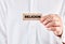 Male hand shows a wooden block with the word religion