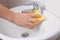 Male hand with sponge cleaning sink