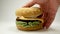Male hand takes a knitted burger on a white background, Close Up