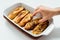 Male hand taking torrijas, typical Spanish sweet fried toasts of sliced bread soaked in eggs and milk on tray isolated.