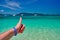 Male hand with thumb up against turquoise sea and azure tropical sky. Concept of an excellent holiday at sea.