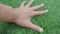 Male hand is touching artificial lawn grass. Hand on green grass. Feels the softness of artificial grass.