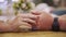 Male hand touching female hand while romantic date in evening restaurant. Woman touching hand girlfriend on table at