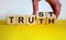 Male hand turns wooden cubes and changes the word `Truth` to `Trust`. Beautiful yellow table, white background. Business conce