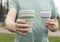 Male hand with two eco reusable cups in hand, giving and offering green silicon coffee mug forward