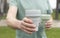 Male hand with two eco reusable cups in hand, giving and offering silicon coffee mug to camera