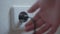 Male hand unplugging plugs from socket on wall. Unrecognizable Caucasian young man disconnecting electrical appliances