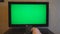 Male hand using a remote control to flipping channels on green screen TV. Arm of man surfing television channels with