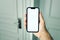 Male hand using smartphone app to unlock apartment door, smart home concept mockup