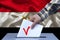 Male hand of a voter lowers the ballot in the ballot box against the background of the national flag of yemen country, concept of