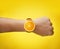 Male Hand Wearing Fruit Orange Watch on Yellow Background