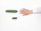 Male hand on a white background reaching for a big cucumber, the concept of increasing the male penis using different