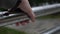 Male hand wipes off raindrops from metal handrail of protective guarding