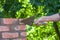 Male hand working with a trowel, repairing a chimney from red bricks on a roof of country house