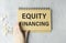 Male hand writing `equity financing` on white