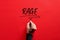 Male hand writing the word rage on red background