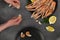 Male hands cleaning boiled langoustines on black plate  on gray concrete table. Served with lemon and spicy herbs. Top