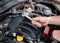 Male hands with combination spanner over the open car bonnet, close up, selective focus