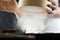 Male hands of a cook sifting flour through a sieve in the kitchen