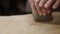 Male hands crumple and roll out piece of clay on table, front view, closeup. Potter prepares clay for processing on