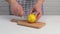 Male hands cut lemon in half on cutting board.