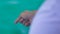 Male hands of fisherman catching fish by fishing line in blue sea close up. Fisherman fishing in sea from sailing boat.