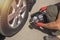 Male hands in glove and portable tire pump for inflating auto wheel. Tyre inflator air compressor with pressure gauge