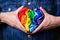 Male hands with heart shaped rainbow lgbtq flag, pride month