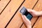 Male hands hold smartphone on brown red glossy boards wooden table. Top view, mockup, close-up