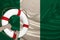 Male hands hold on a white lifebuoy against the background of the silk national flag of the country of Nigeria, the concept of