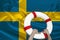 Male hands hold on a white lifebuoy against the background of the silk national flag of the country of Sweden, the concept of