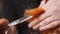 Male hands holding a hair strand and cutting it using scissors and comb. Closeup view of redhead woman`s hair being cut